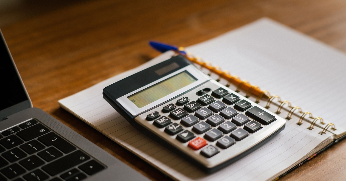 Laptop, calculator, and notebook used to compare affordable employee wellness options