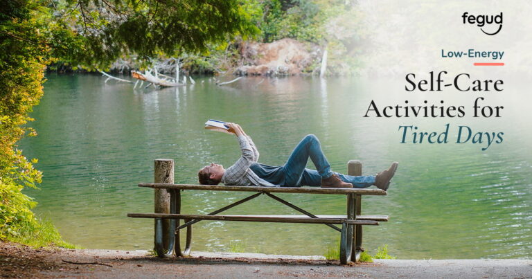 Person reading beside a quiet lake while choosing low-energy self-care activities