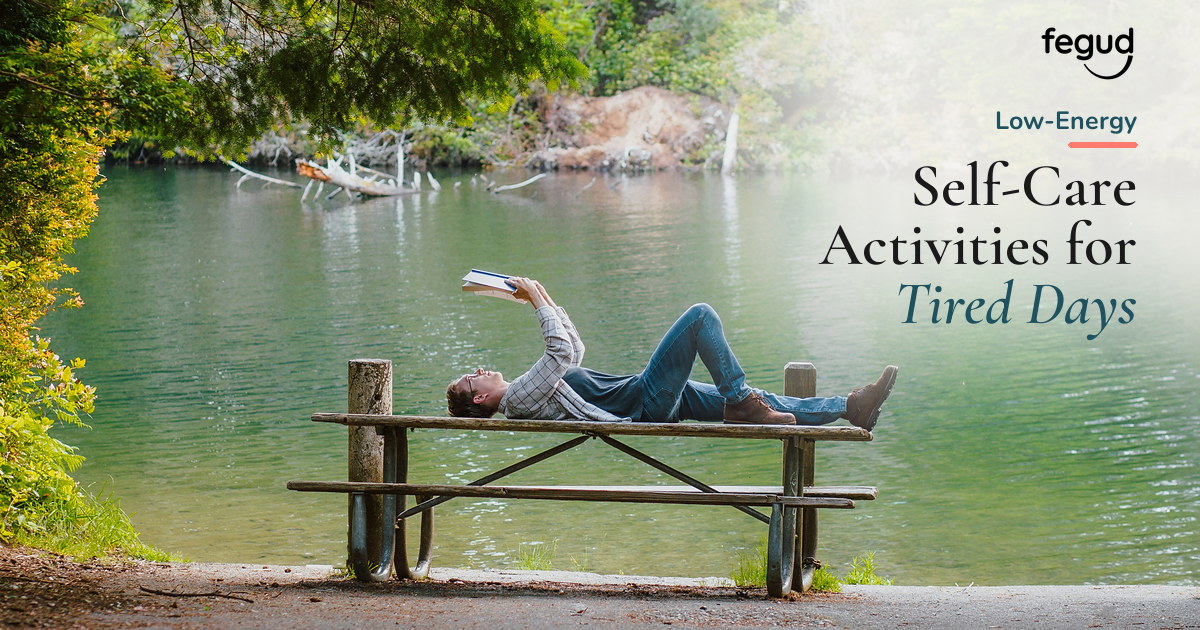 Person reading beside a quiet lake while choosing low-energy self-care activities